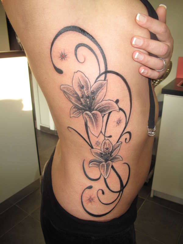 black and gray side tattoo of  tribal and lily tattoo