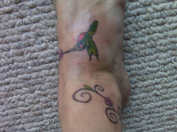 Hummingbird with vine of flowers going around ankle tattoo