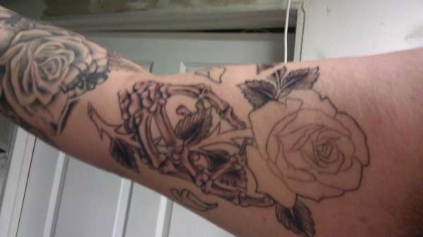 first session skeleton hand holding rose tattoo