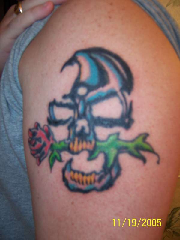 Skull with rose on left arm tattoo
