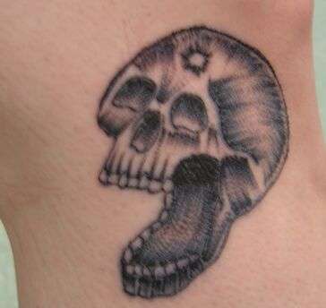 single needle skull with a bullet hole in its head tattoo