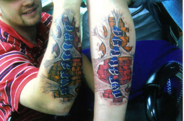 sons name over bricks and streached skin tattoo