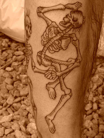 dancing skeletons on johns leg tattoo