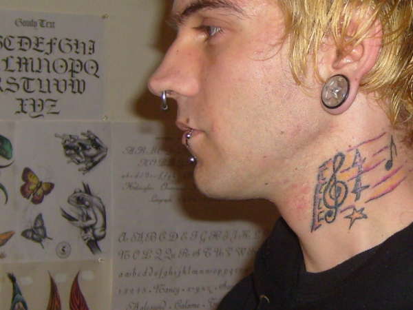 Treble clef on neck with notes tattoo