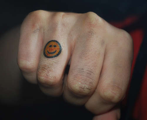 Smiley face on finger tattoo