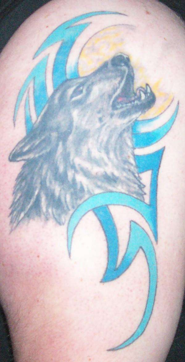 Howling wolf with tribal background tattoo