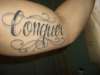 Conquer Lettering bicepts tattoo