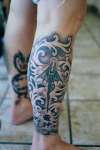blk & grey wash dragon & scrolling on leg tattoo