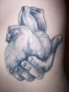 Hand holding heart tattoo