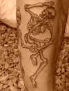 dancing skeletons on johns leg tattoo