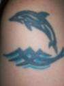 Dolphin jumping out of wave tattoo